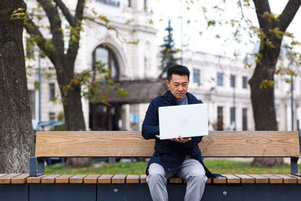 中国商人在笔记本电脑上远程在线工作，亚洲人在办公室外图片下载