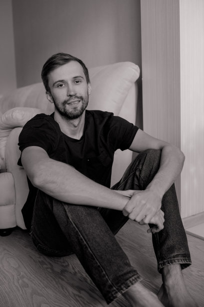 年轻的大胡子男子坐在沙发旁的地板上休息。图片下载