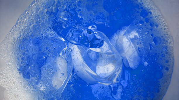 蓝色饮料放入装有冰块的玻璃杯中图片下载