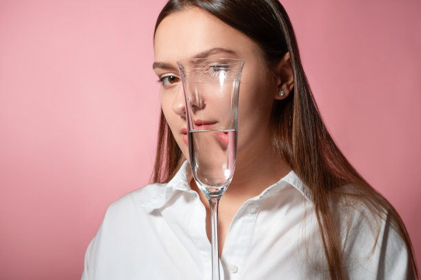 一个年轻的黑发女人的肖像在折射通过水的玻璃杯图片下载