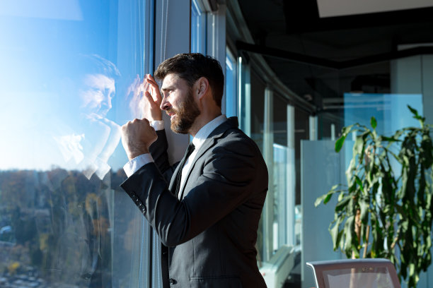 破产的商人老板，沮丧地望着窗外，穿着西装的男人，沮丧和沮丧，在现代的办公室里图片下载