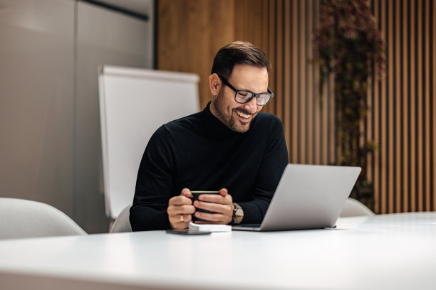 高兴的白人男子，在工作中用一杯咖啡暖手。图片下载