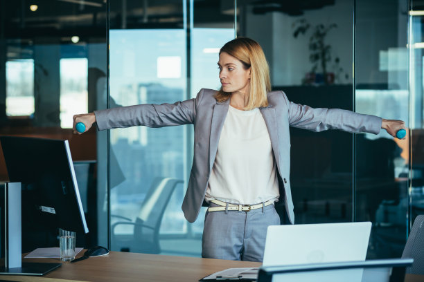 美丽快乐的女人在办公室工作时做运动，在休息时，商业女人监测健康从事健身图片下载