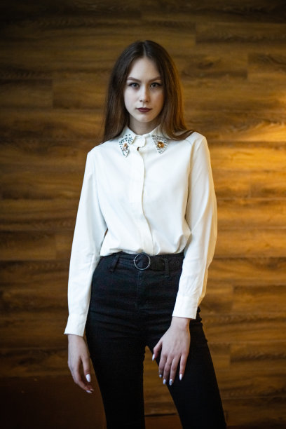 一个年轻的金发女孩，穿着白色的上衣，背景是一堵木墙。图片下载