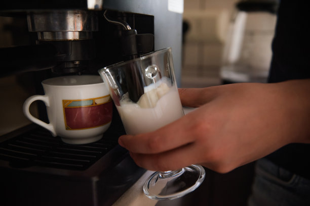 一个年轻人的手用咖啡机煮咖啡。早上在家吃拿铁早餐。图片下载