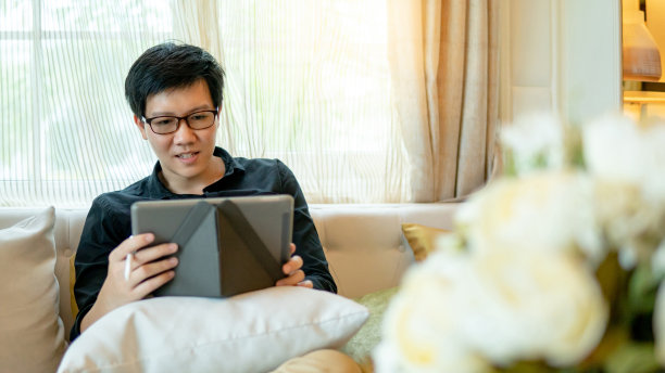 亚洲商人在客厅用数码平板电脑图片下载