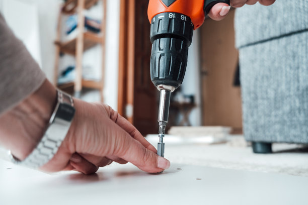 循序渐进的家具组装。一个女人用螺丝刀把一颗螺钉拧到木板上图片下载