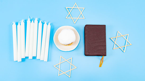 一个大甜甜圈，粉和奶油放在碟子里，九根白蜡烛，一本圣经和三颗星图片下载