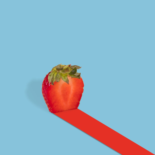 红色草莓叶的一半在明亮的蓝色背景上的红色轨道。维生素，新鲜健康的食品理念。图片下载
