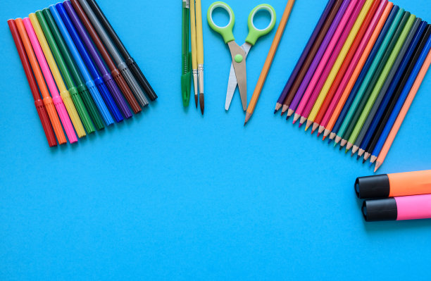 回到学校概念，马克笔，蜡笔，剪刀，钢笔，在蓝色背景上的画笔图片下载