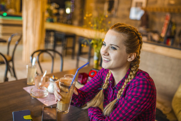 美丽的微笑年轻女子喝咖啡在咖啡店图片下载