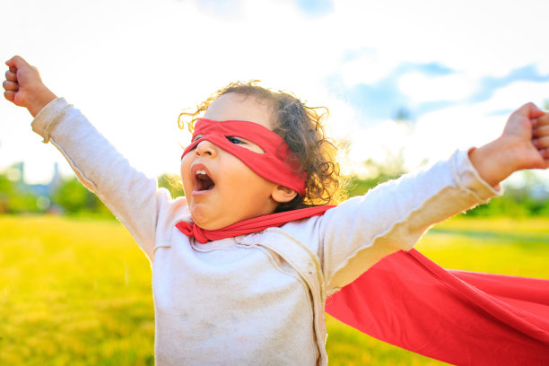 非裔美国小女孩身穿红色服装，戴着眼罩，在夏日公园里扮演英雄图片下载