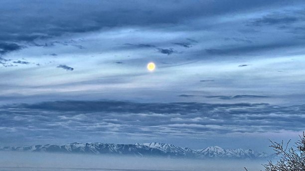 清晨的月亮盘在雪山山峰上升，在冬季雾的股票照片图片下载