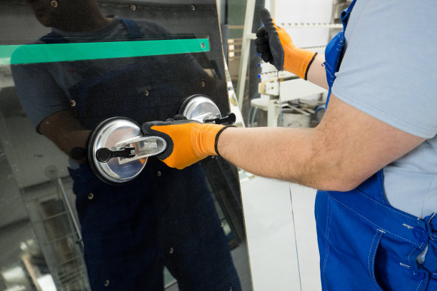 玻璃工在工作场所的专业桌子上用一个特殊的吸盘抓取玻璃图片下载