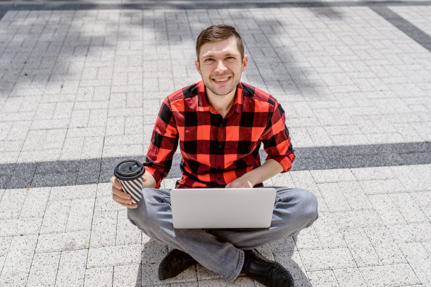 一个年轻的自由职业者正在户外用他的笔记本电脑工作图片下载