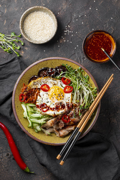 韩国传统菜肴石锅拌饭。碗米饭，香菇，鸡肉，黄瓜和微绿色蔬菜和韩国石锅拌饭酱俯视图。深色背景，垂直照片图片下载