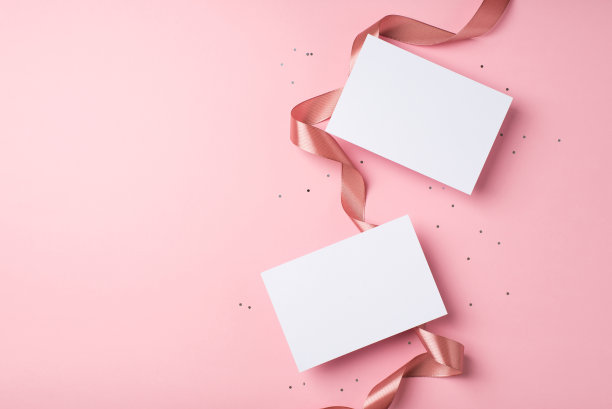 俯视图照片的圣瓦伦丁节装饰卷曲的丝绸丝带，两个字母和亮片在孤立的淡粉色背景copyspace图片下载