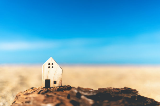 小的家模型在日落海滩沙子纹理背景。复制空间的家庭生活方式和商业地产的概念。图片下载