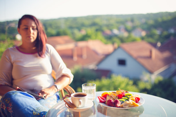 在阳台上享用早餐的女人图片下载