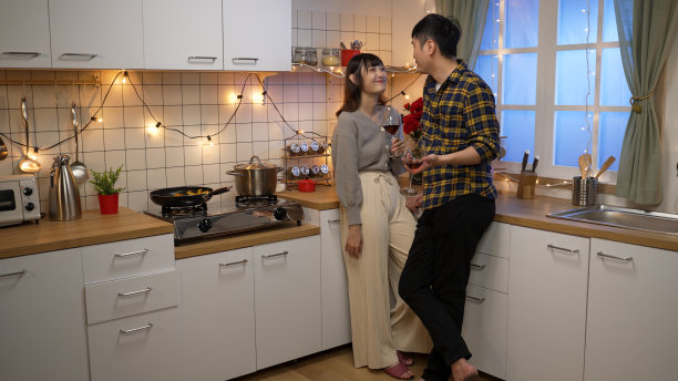 一整段微笑的亚洲男友和女友为情人节干杯，而约会在一个舒适的装饰厨房在家里的晚上图片下载