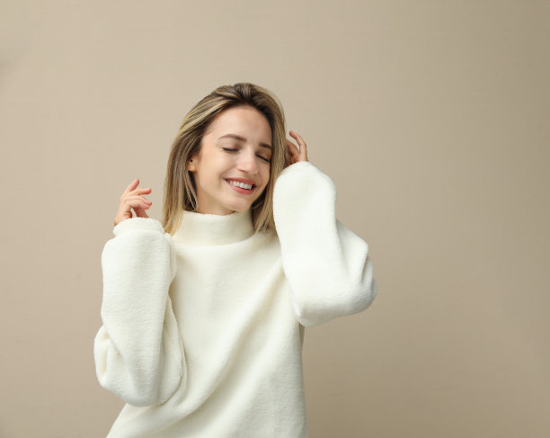 漂亮的年轻女子穿着米色背景的针织毛衣。空间的文本图片下载