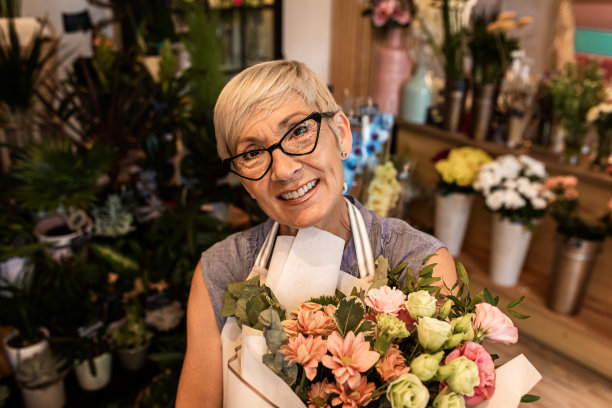 高级女花商的肖像在她的花店。图片下载