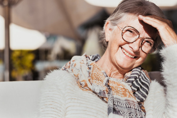 快乐有吸引力的老年人奶奶的肖像奶奶看着相机在阳光下穿白色的毛衣和围巾。微笑的退休妇女戴眼镜享受轻松的时刻图片下载