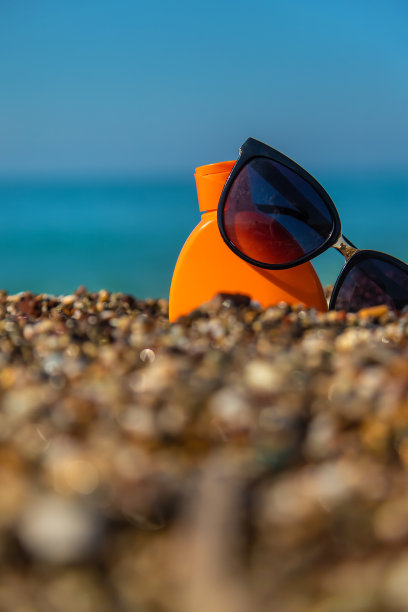 在沙滩上涂防晒霜，戴眼镜。有选择性的重点。图片下载