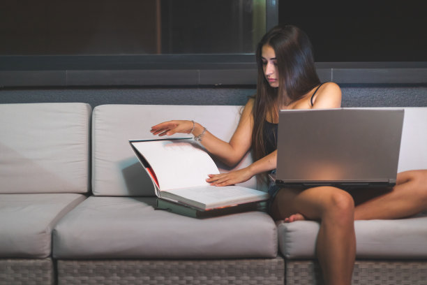 年轻的白种人女人在阳台的沙发上学习。马德里,西班牙。图片下载