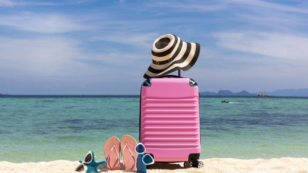 夏天的东西用粉红色的行李放在白色沙滩的背景上，是热带旅游概念的旗帜图片下载