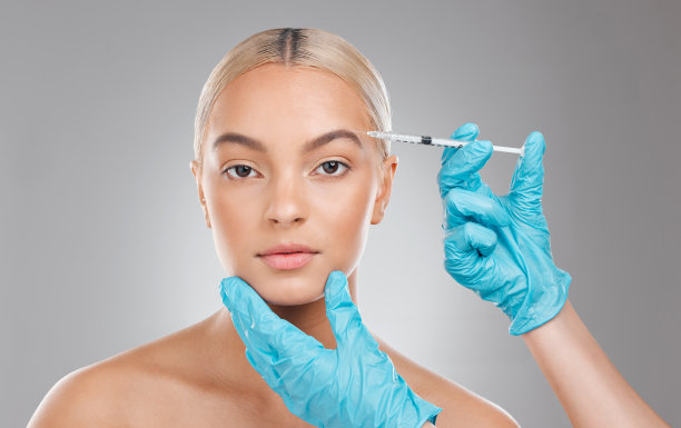 这张照片拍摄的是一名漂亮的年轻女子戴着手套在摄影棚背景下进行面部注射图片下载