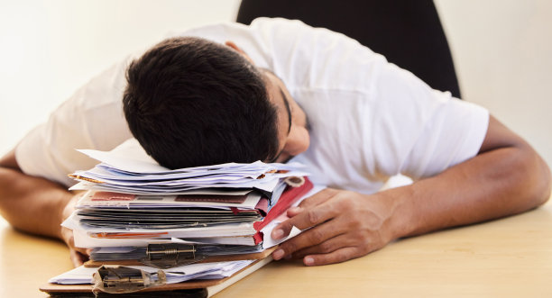 这张照片拍的是一个不认识的男人在家工作时睡在一堆文件上图片下载