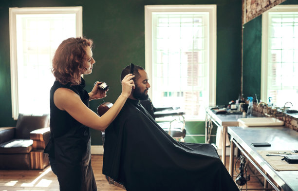 一个英俊的年轻人坐在那里，让理发师给他做头发图片下载