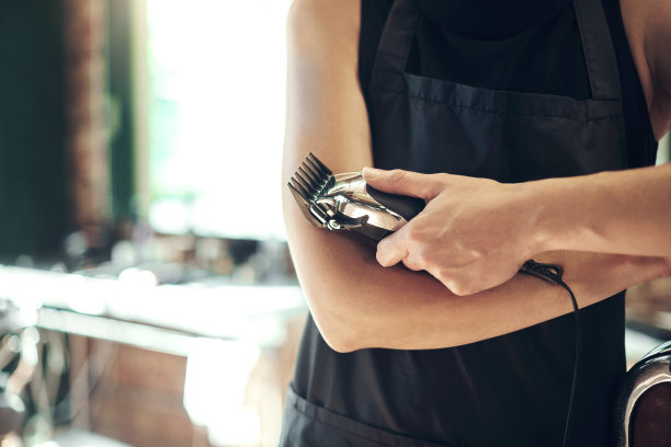 一个不知名的发型师站在她的沙龙里拿着剃须机的照片图片下载