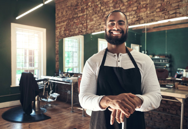一个年轻英俊的理发师独自站在他的沙龙里，拿着扫帚图片下载