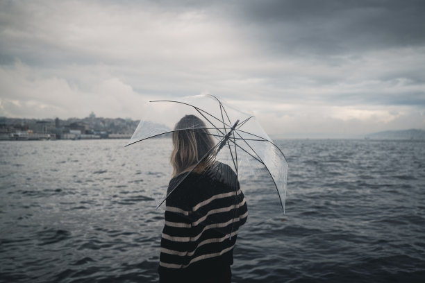 女人撑着透明的伞在水前图片下载