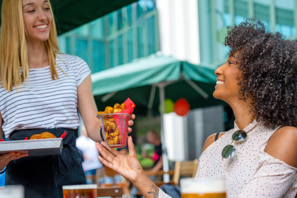 在快餐店为一位非裔美国妇女提供美味的小吃，吃着油炸食品，喝着啤酒图片下载