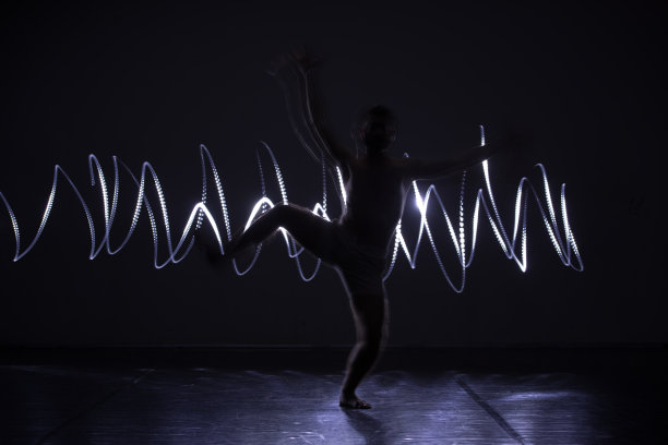 现代舞表演者在蓝色霓虹灯下跳舞，同时做出优雅的动作和壮观的身体艺术表达。图片下载