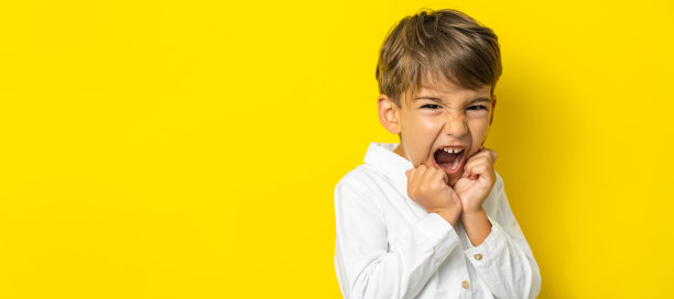 一个四岁的白人小男孩站在黄色背景的工作室拍摄的孩子摆姿势，看着相机复制空间图片下载