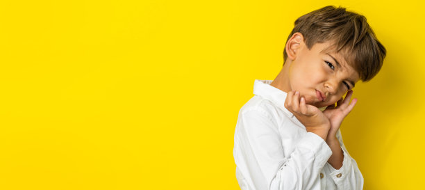 一个四岁的白人小男孩站在黄色背景的工作室拍摄的孩子摆姿势，看着相机复制空间图片下载