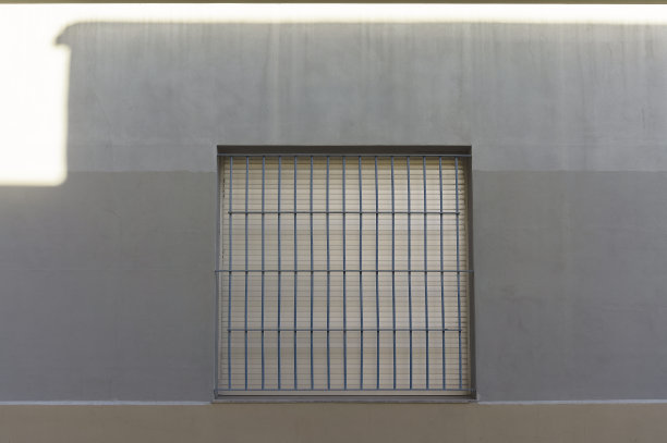 乡村住宅的灰色立面，带有带有白色百叶窗的格子窗。为了防止盗窃，铁条是必要的。图片下载