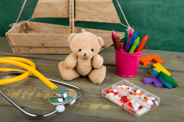 足科医生工作场所——玩具熊、听诊器和木制办公桌上的药品——儿童保健概念图片下载