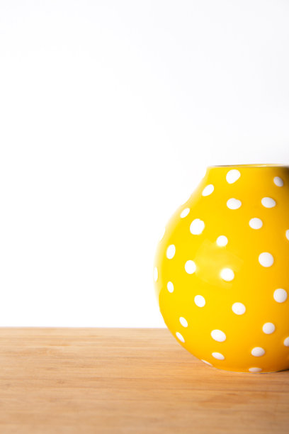 亮黄色花瓶，白色背景上点缀着小圆点图片下载