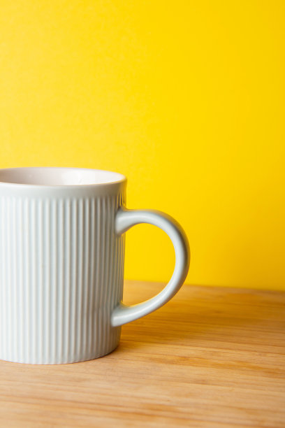 蓝色陶瓷杯在明亮的黄色背景图片下载