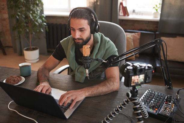 英俊的年轻中东男子在高处拍摄的横版照片，穿着休闲装独自坐在阁楼房间里为视频博客创作内容图片下载