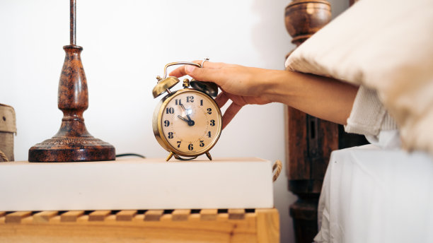 一个面目全非的年轻女人在早上关掉一个老式闹钟的手图片下载