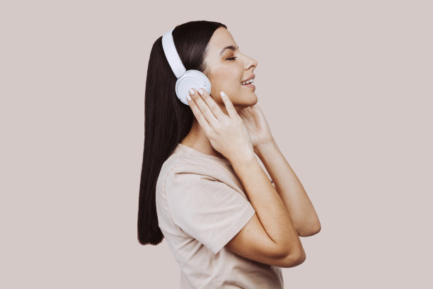 美丽的女人听音乐，带着耳机在工作室图片下载