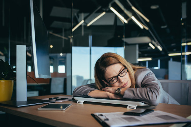 美丽的金发女商人在桌子上睡觉，在她的工作场所的电脑，在一个现代的办公室，工作到很晚，超负荷工作图片下载