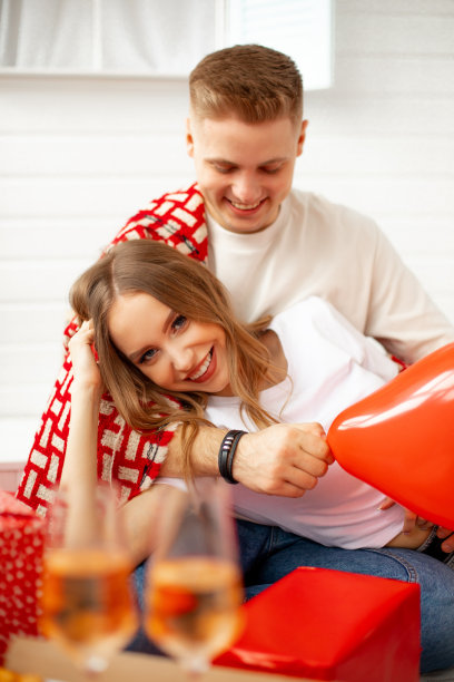 微笑的金发年轻男子和女子在白色与红色格子的肩膀拥抱，庆祝情人节图片下载
