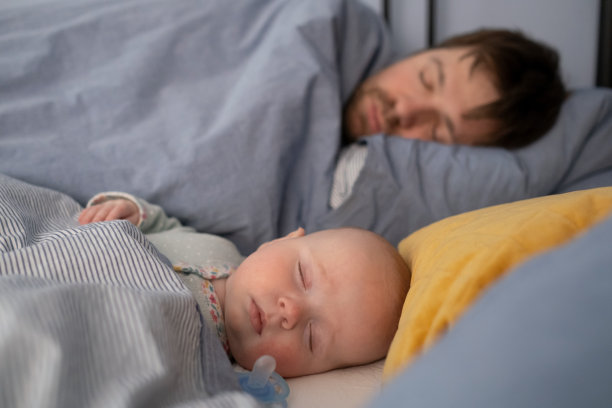 熟睡的父亲和可爱的孩子一起躺在床上。图片下载